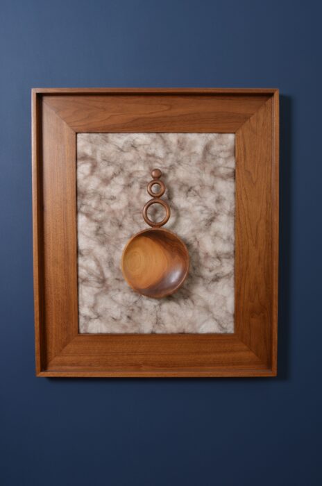 Rounded walnut sculpture mounted over marbled felt and wool, enclosed in a walnut frame.