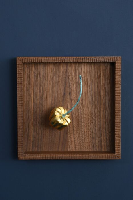 Hand-carved basswood pepper covered in gold leaf with a hand-forged green patinated copper stem, presented in a handcrafted walnut frame.