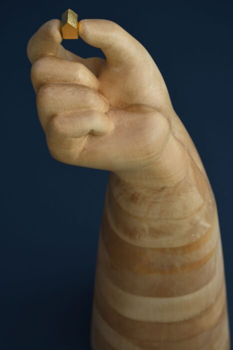 Wooden sculpture of big hand holding a small house above